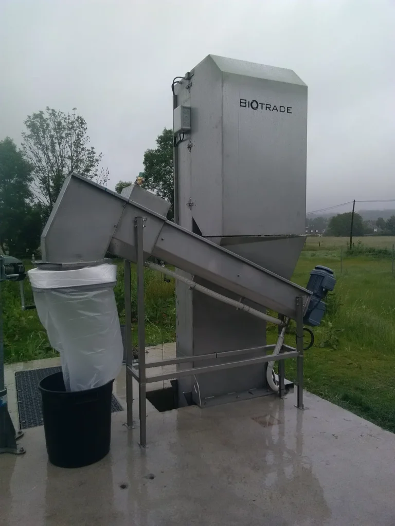 Vis de compactage Biotrade DV 800 installée en station d'épuration rurale par temps de pluie avec sac de collecte Longopac et bac roulant