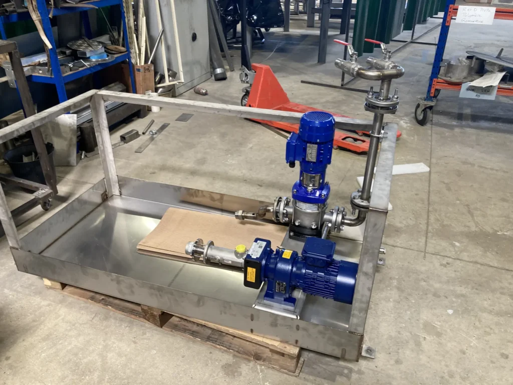 Bac de préparation de polymère inox avec pompe doseuse bleue et tuyauterie, en cours d'assemblage en atelier Biotrade