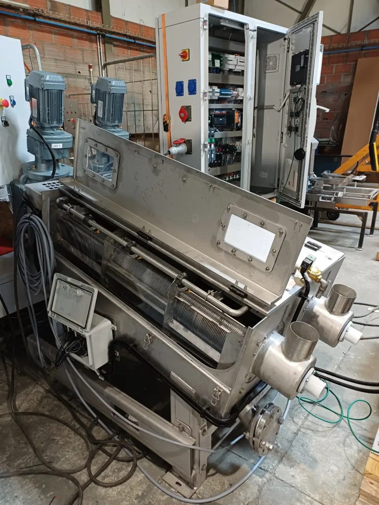 Presse à vis Biopress ouverte en atelier avec vis de compression visible, armoire électrique en arrière-plan