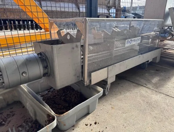 Sortie de boues déshydratées en gâteau compact depuis une presse à vis Biotrade lors d'un essai pilote