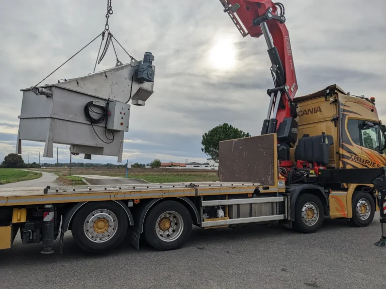 Dégrilleur matières de vidange Biotrade suspendu par grue Fassi au-dessus du plateau d'un camion Scania Thuries lors de la mise en place