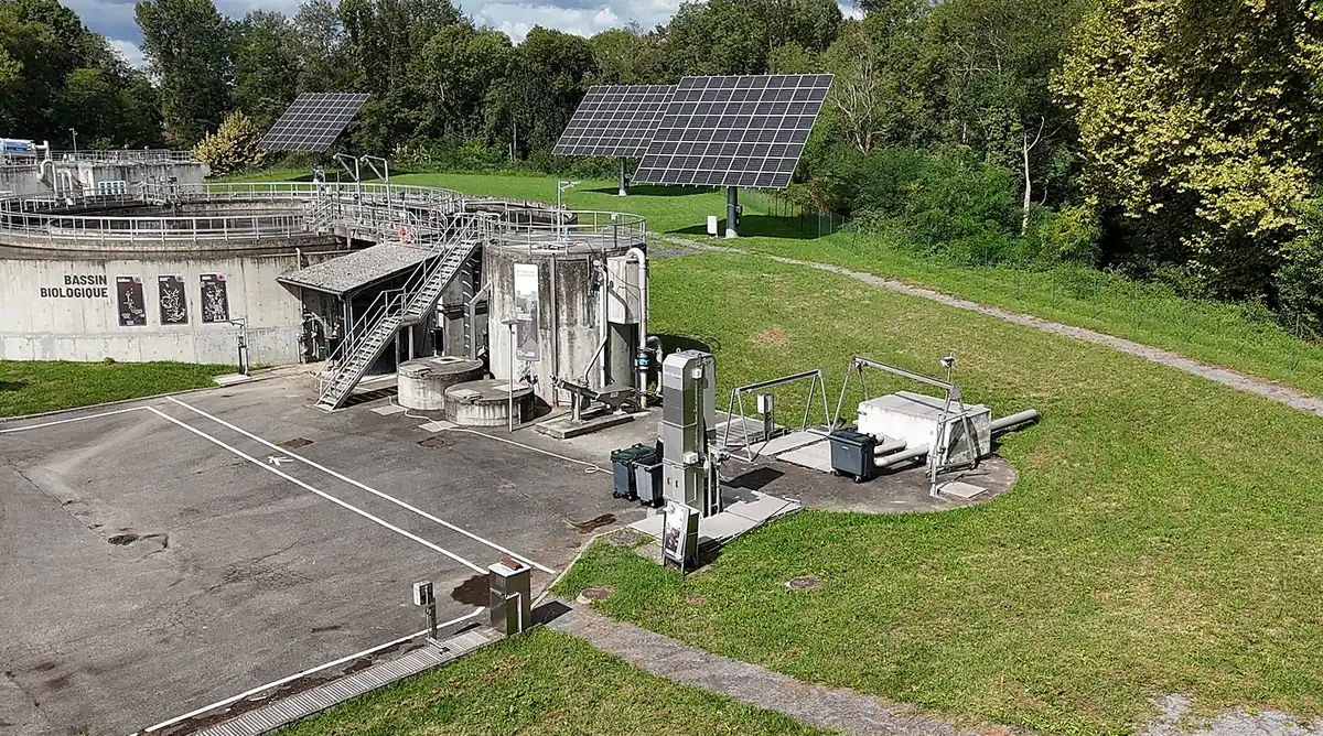 Vue aérienne drone d'une station d'épuration avec le dégrilleur BioScreen DS Biotrade au centre, bassin biologique et panneaux solaires visibles